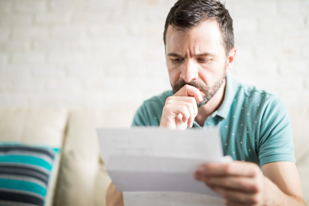 Man looking at his utility bills, concerned about the high prices