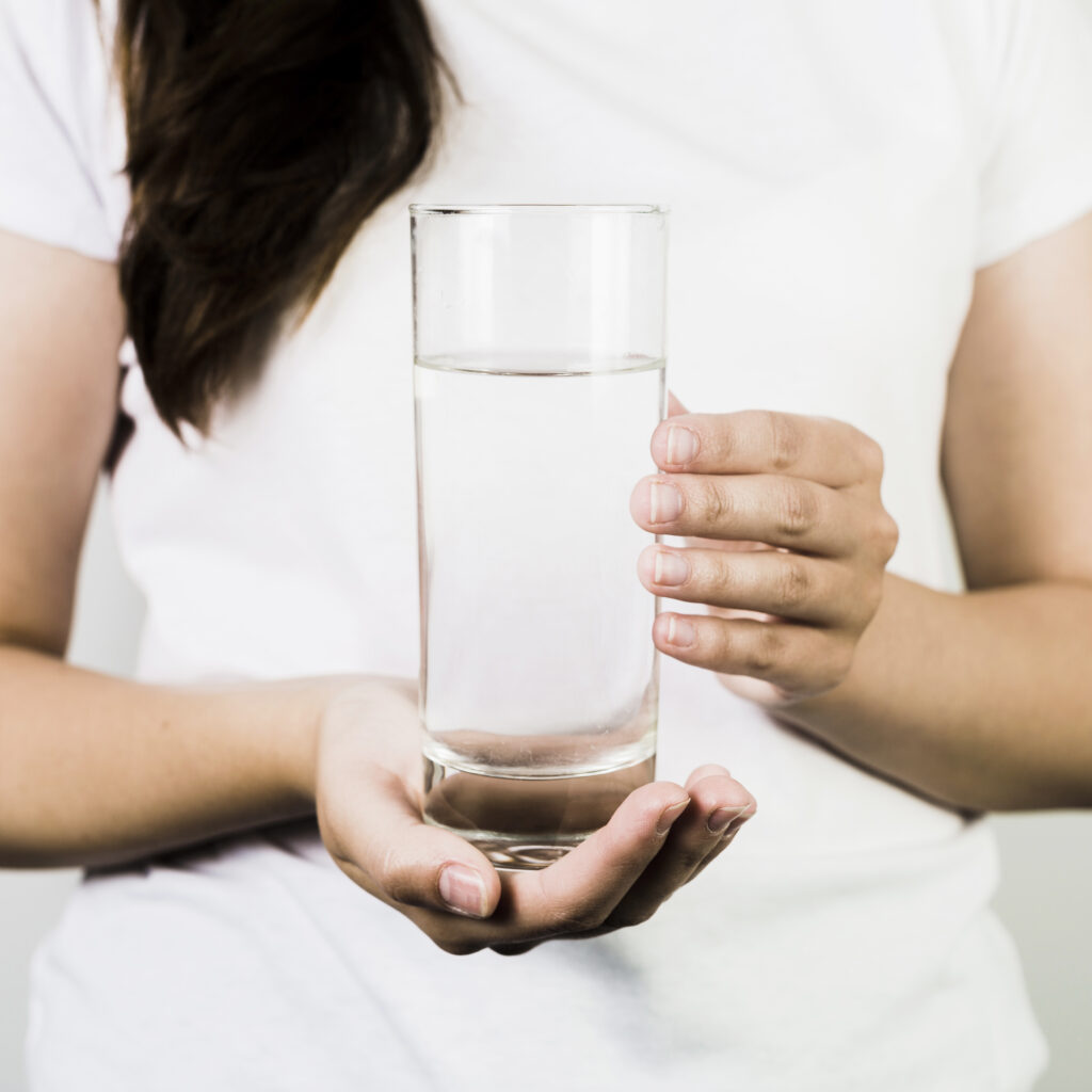 female holding clear glass of water