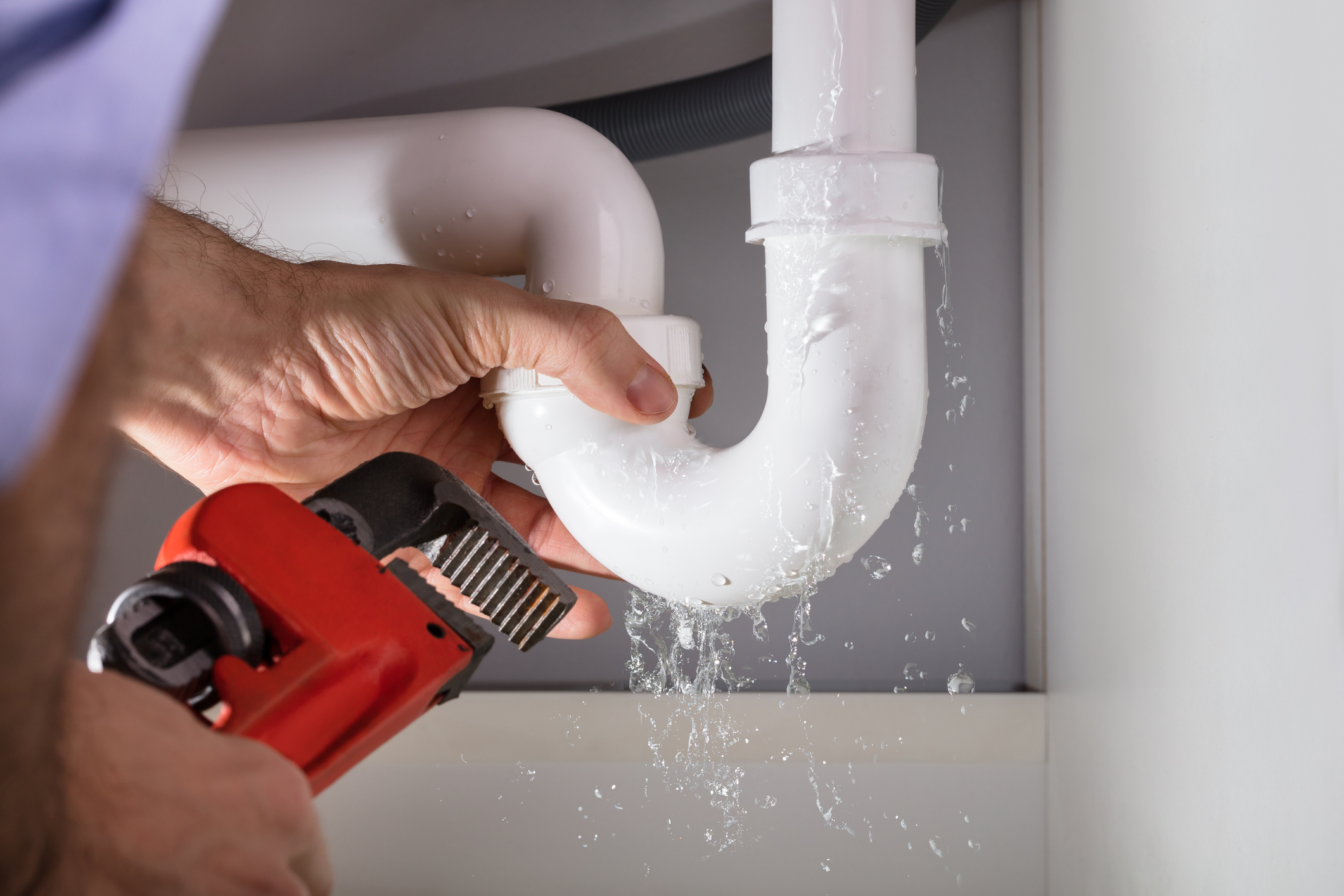 An expert plumber skillfully repairs a leaking pipe using a tool.