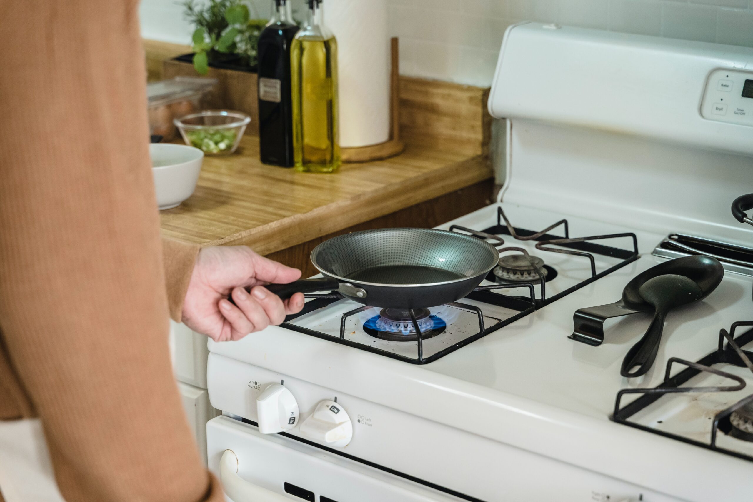 person putting a pan on a lit gas stove burner